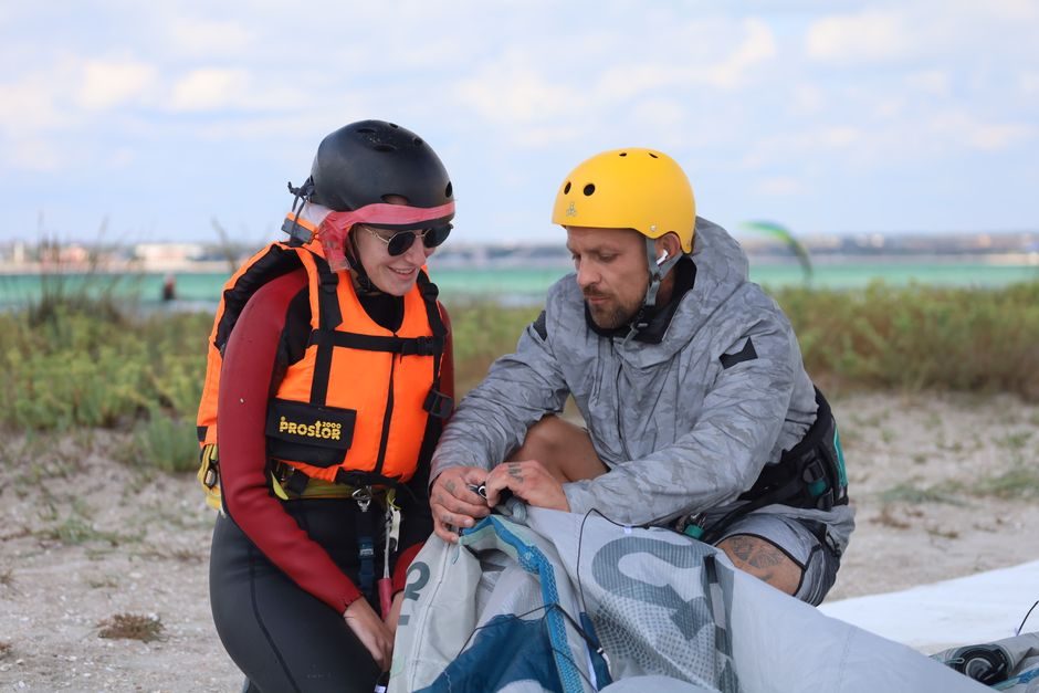 Instructor showing a kitesurf student how to handle the kite on the beach