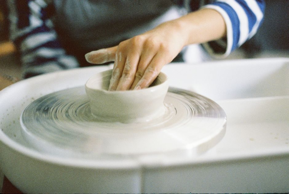 Hands shaping a clay bowl on a pottery wheel