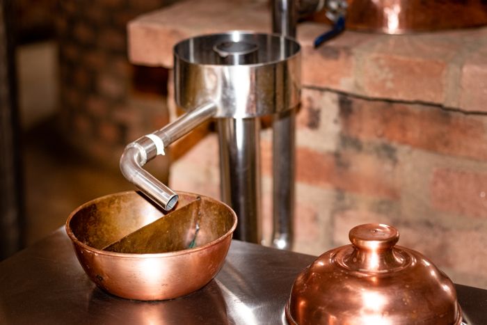 Copper distilling apparatus against a brick wall
