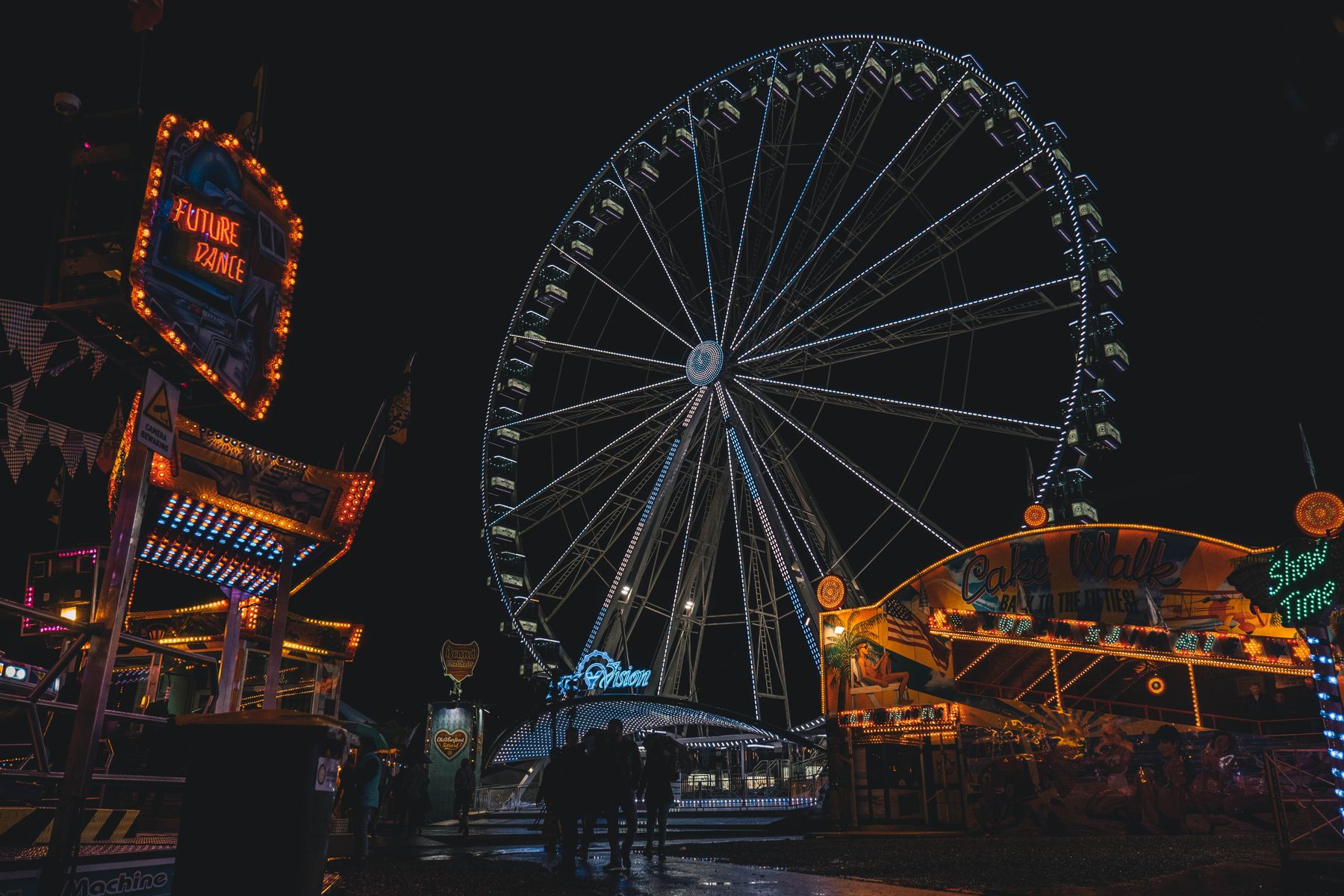 Fairground lights and a lit Ferris wheel at night
