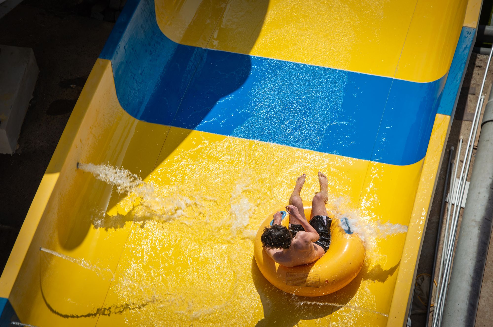 Swimmer on an inflatable ring sliding down a yellow and blue waterslide
