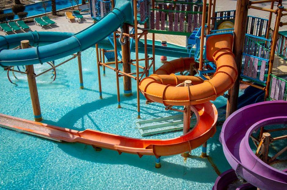 Orange and purple waterslides above a bright blue pool