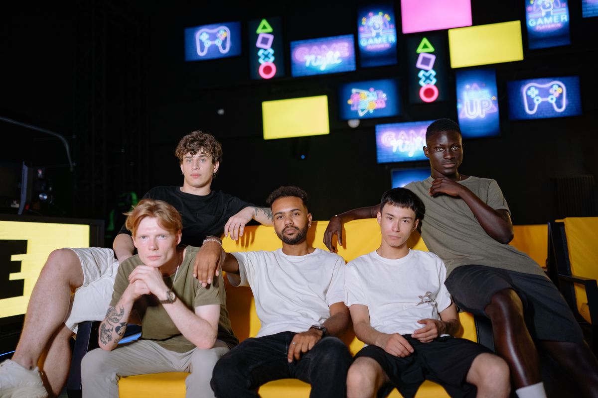 Group of friends laughing on a yellow sofa in a neon game room