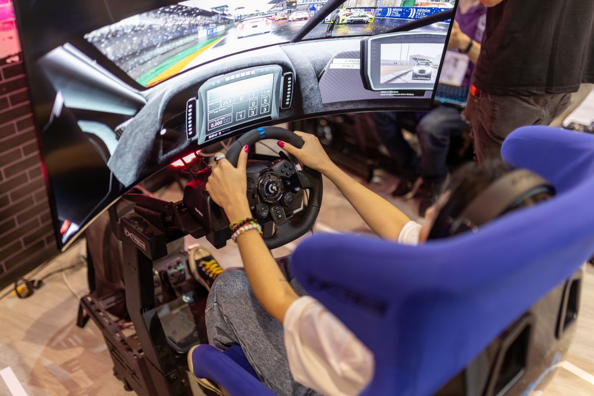 Player driving in a racing simulator with a curved screen and blue bucket seat